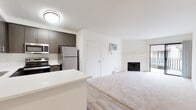 Located at 10445 Mast Blvd in Santee, California, this single-floor unit offers a well-designed layout with modern finishes throughout. The kitchen is a standout feature, showcasing dark wood-tone cabinetry, crisp white countertops, a peninsula with additional storage, and a full suite of stainless steel appliances including a refrigerator, electric range, and microwave. Light wood-style flooring runs through the kitchen and entry areas, creating a clean, contemporary feel.

The open living area transitions seamlessly from the kitchen and features plush carpeting, a wall-mounted air conditioning unit, and a fireplace with a classic white mantel. A sliding glass door provides access to an outdoor balcony, allowing natural light to fill the space.

The bedrooms are carpeted and well-proportioned, each offering mirrored sliding closet doors for added storage and functionality. Windows bring in natural light and provide views of the surrounding community, which features tile-roofed residential buildings.

The bathroom is finished with light wood-style flooring, a dark wood-tone vanity with a white countertop, a large mirror, and modern lighting fixtures. The overall design of this unit combines practical functionality with contemporary aesthetics, making it a comfortable and attractive living space.