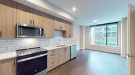 Located at 903 Peachtree St NE in the heart of Atlanta, Georgia, this modern single-floor unit offers a well-designed open-concept layout that seamlessly connects the kitchen and living area. The kitchen is a standout feature, outfitted with light wood shaker-style cabinetry, black hardware accents, white quartz countertops, and a classic subway tile backsplash. Stainless steel appliances — including a range, over-the-range microwave, dishwasher, and refrigerator — complete the functional and stylish space. Rich, dark hardwood-style flooring flows throughout the main living areas, adding warmth and continuity to the design. Large floor-to-ceiling windows flood the living space with natural light and offer sweeping views of the surrounding Atlanta cityscape. The bedroom continues the clean, modern aesthetic with the same large windows and neutral walls. The bathroom features light tile flooring, a wood-toned vanity with matching hardware, and a tiled shower/tub combination. A stacked in-unit washer and dryer provides added convenience. The overall ambiance is clean, contemporary, and bright — well-suited for urban living in one of Atlanta's most vibrant neighborhoods.