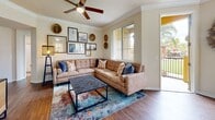 Located at 825 E Palomar St in Chula Vista, this single-floor residence offers a thoughtfully designed layout with warm, neutral tones and wood-style flooring carried consistently throughout. The living room serves as a comfortable gathering space, featuring crown molding, a ceiling fan, and large windows that invite natural light and frame views of the palm tree-lined community grounds. A sliding door provides direct access to an outdoor area overlooking the landscaped green space below.

The dining area sits adjacent to the living room, benefiting from its own window and an intimate, well-proportioned setting. The kitchen is equipped with ample cream-colored cabinetry, granite-style countertops, a double basin sink, and black appliances including a refrigerator, range, and over-the-range microwave.

The bedrooms each feature wood-style flooring, ceiling fans or windows with natural light, and a calm, restful atmosphere. The bathroom includes a granite-topped vanity with white cabinetry, a full tub-shower combination, and rich wood-tone flooring. A dedicated in-unit laundry area houses a full-sized washer and dryer with overhead shelving for added storage convenience.