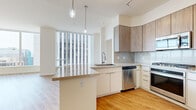 Located at 44 W Monroe St in the heart of downtown Phoenix, this modern high-rise unit offers a thoughtfully designed single-floor layout with an open, airy feel throughout. Light hardwood flooring flows continuously across the living spaces, complemented by crisp white walls and high ceilings that enhance the sense of volume.

The open-concept kitchen and living area serves as the centerpiece of the unit. The kitchen is outfitted with contemporary two-tone cabinetry — white lower cabinets paired with warm wood-finish uppers — stone countertops, a peninsula island with seating potential, and a full suite of stainless steel appliances including a gas range, dishwasher, microwave, and refrigerator. Pendant lighting above the island adds a refined touch.

Multiple living areas are bathed in natural light from expansive floor-to-ceiling windows, which frame sweeping panoramic views of the Phoenix skyline and surrounding desert cityscape. A balcony extends the living space outdoors, providing direct access to the open-air views.

The unit includes two well-appointed bathrooms, one of which features a glass-enclosed walk-in shower with tile surround and a stacked washer and dryer for in-unit convenience. Two closets — including a generously sized walk-in — provide ample storage. A hallway efficiently connects all areas of the home, ensuring a logical and comfortable flow throughout.