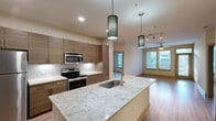 Located at 900 Grange Hall Dr in Euless, TX, this well-appointed 2-bedroom, 2-bathroom residence offers a thoughtfully designed single-floor layout. The open-concept kitchen serves as the heart of the home, showcasing a large granite-topped island with an undermount sink, sleek wood-grain cabinetry, a white subway tile backsplash, and a full suite of stainless steel appliances including a refrigerator, range, and over-the-range microwave. Stylish pendant lighting adds a modern touch above the island. The kitchen flows seamlessly into the living room, which features warm wood-style plank flooring, a ceiling fan, and windows with exterior access that bring in generous natural light. Both bedrooms are carpeted and include ceiling fans, windows overlooking the outdoors, and dedicated closets with built-in shelving systems for organized storage. The bathrooms are finished with large-format tile flooring, wood-toned vanities, granite countertops, and wide framed mirrors. A connecting hallway ties the bedrooms and bathrooms together efficiently. Throughout the residence, neutral tones and contemporary finishes create a clean, cohesive aesthetic that is both functional and inviting.