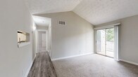 Located at 3475 Pleasantbrook Village Ln in Atlanta, GA, this 2-bedroom, 1-bathroom home offers a well-organized single-level layout with a thoughtful mix of flooring and architectural detail throughout. The living room is a standout space, featuring dramatic vaulted ceilings that lend an open, airy feel, along with a built-in wall niche and access to a private balcony overlooking greenery. Wood-look vinyl flooring anchors the living and kitchen areas, creating a clean, cohesive look. The kitchen is efficiently designed with white cabinetry, granite-style countertops, stainless steel appliances including a refrigerator and range, and a dedicated overhead light fixture. Both bedrooms are carpeted in neutral tones and filled with natural light from window treatments. The primary bedroom is a comfortable size and features its own dedicated closet with built-in shelving and hanging rods, offering ample storage. The second bedroom includes a sliding-door closet and connects conveniently to the hallway. The full bathroom is clean and functional, featuring a tub-shower combo with a built-in niche and wood-look flooring. Neutral gray-toned walls throughout the home provide a versatile backdrop. A connecting hallway ties all rooms together seamlessly.