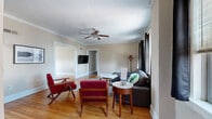 This single-story, 3-bedroom, 2-bathroom home offers a thoughtfully organized layout with a blend of classic architectural details and practical living spaces. The living room welcomes with warm hardwood flooring, elegant crown molding, a ceiling fan, and natural light filtering through draped windows — creating a relaxed yet refined gathering space. Adjacent, the dining room continues the hardwood floors and crown molding, brightened by a large window with views outside. The kitchen is well-equipped with dark cabinetry, subway tile backsplash, granite-style countertops, track lighting, and a pantry, all set on clean tile flooring. Both bathrooms are finished with large-format marble-style tile on the floors and walls, paired with dark vanities and granite countertops for a polished look. The three bedrooms are carpeted and filled with natural light from generously sized windows, several of which frame urban cityscape views. The primary bedroom offers a comfortable sense of space. Additional features include five closets, a dedicated laundry room, a utility room, and two hallways connecting the home's well-structured floor plan.