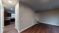 Located in Nashville, TN, this two-story residence offers a thoughtfully laid-out interior with distinct finishes across each level. The main floor features rich, dark hardwood-style flooring throughout the living and kitchen areas, complemented by neutral gray walls and crisp white trim and baseboards. The spacious living area provides an open feel, with a staircase featuring white balusters leading to the upper level. Crown molding adds a refined detail to the main living space.

The kitchen is well-appointed with dark espresso cabinetry, granite-style countertops, and stainless steel appliances including a refrigerator and range. Recessed lighting illuminates the space, and the hardwood-style flooring continues seamlessly from the living area. A half bathroom on the main floor provides added convenience, finished with matching hardwood-style flooring and clean white fixtures.

Upstairs, the bedrooms are finished with wall-to-wall carpet and continue the neutral color palette. The primary bedroom features vaulted ceilings with a ceiling fan, enhancing the sense of space. Additional bedrooms include windows with blinds that allow natural light. Crown molding is present in the upper-level rooms, adding consistency throughout the home.