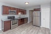 Located at 23237 Providence Dr in Southfield, Michigan, this single-floor residence offers a thoughtfully designed layout with a clear separation between living, sleeping, and functional spaces. The kitchen is a standout area, featuring rich dark-brown cabinetry, light granite-style countertops, and a full suite of stainless steel appliances including an electric range, over-the-range microwave, and refrigerator. Light wood-look flooring runs through the kitchen, providing a clean, modern aesthetic that transitions naturally into the adjoining living areas.

The living space is generously proportioned, featuring plush carpeting and large windows dressed with vertical blinds that allow ample natural light to fill the room. Neutral gray walls throughout the unit create a cohesive, move-in-ready atmosphere.

The bedrooms are carpeted and well-sized, each offering closet storage with wire shelving systems. The primary bedroom includes access to a walk-in closet and an en-suite bathroom. The bathrooms are finished with dark vanity cabinetry, white countertops, and light wood-look tile flooring. One bathroom features a full soaking tub with a shower, while the second offers a streamlined layout with a vanity and mirror.