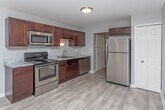 Located at 23237 Providence Dr in Southfield, Michigan, this single-floor residence offers a thoughtfully designed layout with a clear separation between living, sleeping, and functional spaces. The kitchen is a standout area, featuring rich dark-brown cabinetry, light granite-style countertops, and a full suite of stainless steel appliances including an electric range, over-the-range microwave, and refrigerator. Light wood-look flooring runs through the kitchen, providing a clean, modern aesthetic that transitions naturally into the adjoining living areas.

The living space is generously proportioned, featuring plush carpeting and large windows dressed with vertical blinds that allow ample natural light to fill the room. Neutral gray walls throughout the unit create a cohesive, move-in-ready atmosphere.

The bedrooms are carpeted and well-sized, each offering closet storage with wire shelving systems. The primary bedroom includes access to a walk-in closet and an en-suite bathroom. The bathrooms are finished with dark vanity cabinetry, white countertops, and light wood-look tile flooring. One bathroom features a full soaking tub with a shower, while the second offers a streamlined layout with a vanity and mirror.