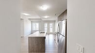Located at 7711 Macleod Trail SW in Calgary, this thoughtfully designed 2-bedroom, 2-bathroom residence offers a well-organized layout across a single level. Light-toned laminate flooring flows consistently throughout, creating a clean and cohesive aesthetic from room to room.

The open-concept kitchen serves as the heart of the home, featuring warm wood-grain cabinetry that reaches full ceiling height, stainless steel appliances including a refrigerator, electric range, and built-in microwave, white quartz countertops, a subway tile backsplash, and a peninsula with an integrated sink — ideal for both cooking and casual dining.

The primary bedroom is a comfortable, well-proportioned retreat with dual windows that invite natural light and views of the surrounding modern residential development. The second bedroom is equally bright, featuring its own window with outdoor views.

Both bathrooms are finished in a consistent modern style, each offering a soaker tub and shower combination with tile surrounds, a wood-grain vanity with a white countertop, and a large mirror with stylish overhead lighting.

A private balcony extends the living space outdoors, overlooking a landscaped courtyard complete with a tennis court and communal pergola area. The building's contemporary exterior blends stone, panel, and glass finishes for strong curb appeal.