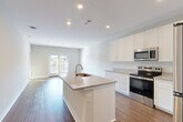 Located at 7105 Hall Rd in Union City, GA, this well-appointed one-bedroom, one-bathroom residence offers a thoughtfully designed open-concept layout across a single floor. Wood-look flooring flows seamlessly throughout, creating a warm and cohesive aesthetic.

The heart of the home is the combined kitchen, dining, and living area, where a central island with a granite countertop and undermount sink serves as a functional focal point. Crisp white shaker cabinetry extends to the ceiling for generous storage, while stainless steel appliances — including a refrigerator, electric range, and over-the-range microwave — complete the modern kitchen. French doors in the living area invite natural light and provide outdoor access with pleasant views of the surrounding greenery.

The spacious bedroom features a ceiling fan, a large window with natural light, and direct access to two closets, offering ample storage. The full bathroom is finished with a granite-topped double vanity, white cabinetry, a large mirror, and a full tub/shower combination. A dedicated utility room and hallway round out the floor plan. The clean, neutral palette and modern finishes give the entire space a fresh, move-in-ready feel.