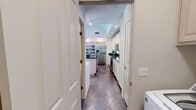 This thoughtfully designed single-story home offers a seamless blend of comfort and functionality across its well-proportioned layout. The living room is a standout space, anchored by a bold fireplace set beneath a graceful arched ceiling. Built-in shelving flanks the room, providing both storage and display space, while plush carpeting adds warmth underfoot.

The kitchen is a bright, well-equipped space featuring white cabinetry extending to the ceiling, dark granite countertops, stainless steel appliances, and a central island with bar seating. The adjoining dining area benefits from large sliding glass doors that flood the space with natural light and provide direct access to an outdoor patio.

Distinctive slate tile flooring in a diagonal pattern flows through the kitchen, dining area, hallways, and laundry room, lending an earthy, cohesive aesthetic throughout. The in-unit laundry room is conveniently located and offers additional cabinetry for storage.

The primary bedroom impresses with soaring vaulted ceilings, a ceiling fan, and sliding glass doors opening to the outdoors. Secondary bedrooms are comfortably sized with soft carpeting. The bathrooms are finished with white cabinetry, white countertops, and gold-tone fixtures. The home's open, airy design and varied ceiling heights give the entire space a sense of expansiveness.
