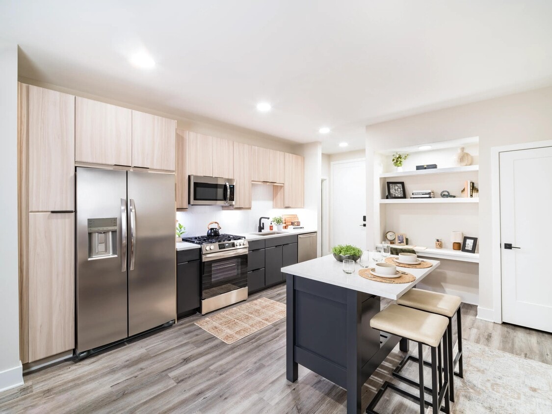 A light-filled kitchen with an oversized island, open shelving, and clean-lined finishes that support everyday cooking and casual dining. - Modera Westside Trail