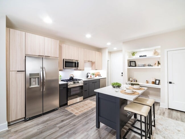 A light-filled kitchen with an oversized island, open shelving, and clean-lined finishes that support everyday cooking and casual dining. - Modera Westside Trail Apartments