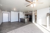 This two-story residence offers a thoughtfully designed layout spread across two levels. The main floor features an open-concept living and kitchen area, where wood-look hard flooring flows throughout. A ceiling fan with integrated lighting anchors the living space, which connects seamlessly to a functional kitchen equipped with dark cabinetry, a center island with a sink, and black appliances including a refrigerator, range, and over-the-range microwave. A dedicated half bathroom on the main level includes a dark wood vanity with a light stone-topped countertop and wood-look flooring. The entry foyer provides a welcoming transition into the home with clean lines and hard flooring. A sliding glass door on the main level opens to an outdoor patio area, bringing in abundant natural light. Upstairs, multiple bedrooms are finished with plush carpet and feature windows overlooking the surrounding neighborhood. Each bedroom offers a comfortable, well-proportioned layout with ample wall space. The upper level is served by a full bathroom complete with a tub-shower combination, a single-sink vanity with a light countertop, and wood-look tile flooring. Throughout the home, a neutral color palette of soft whites and warm grays creates a clean, modern ambiance.