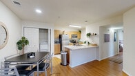 Located at 1920 Exchange Dr in Greenville, NC, this single-floor unit offers four bedrooms and four bathrooms within a well-organized, efficiently designed layout. The open-concept living area seamlessly connects the living room, dining space, and kitchen, creating a social and functional hub. The kitchen is equipped with stainless steel appliances—including a refrigerator, microwave, and range—complemented by warm wood-tone cabinetry and a central island with a marble-style countertop and integrated sink. Wood-style flooring flows throughout the main living areas and hallway, lending warmth and continuity to the space. The living room features a sliding glass door that opens to a private patio, allowing natural light to fill the room. Each bedroom is comfortably sized, featuring large windows, wood-style flooring, and sliding mirrored closets with built-in wire shelving for organized storage. The bathrooms are finished with tile flooring, warm wood cabinetry, and tub-shower combinations. A dedicated laundry area with washer and dryer hookups, a pantry, and five closets provide practical, everyday convenience. The hallway connects all rooms cleanly, contributing to a logical and livable floor plan throughout.