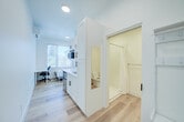 Located at 2445 San Pablo Ave in Berkeley, CA, this efficiently designed one-bedroom, one-bathroom unit offers a thoughtful layout that maximizes every inch of its compact footprint. Light wood flooring runs throughout, lending warmth and visual continuity across all areas of the space.

The kitchenette is neatly arranged along one wall, featuring white shaker-style cabinetry with black hardware, a marble-look countertop, a single-basin sink with a matte black faucet, a built-in microwave, and under-counter appliances — providing all essential cooking conveniences in a streamlined design.

Adjacent to the kitchen, a built-in entryway organizer with hooks and a bench offers practical storage and a welcoming transition into the unit. A tall white cabinet with a full-length mirror adds both storage and functionality.

The bedroom is a cozy, well-lit retreat with large windows that frame views of the surrounding Berkeley neighborhood and lush greenery. A wall-mounted mini-split unit provides individual climate control, and the clean white walls keep the room feeling open and airy. A closet with a paneled door offers dedicated storage.

The bathroom is clean and minimalist, featuring a shower with curtain, a toilet, and light wood flooring consistent with the rest of the unit. The all-white palette creates a crisp, fresh atmosphere throughout this well-appointed Berkeley home.
