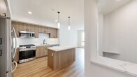 This thoughtfully designed one-bedroom, one-bathroom unit in San Diego's Mission Valley neighborhood offers a well-appointed single-floor layout with modern finishes throughout. The open-concept kitchen serves as a central highlight, featuring warm wood-toned cabinetry, white subway tile backsplash, a quartz-topped island with pendant lighting, and stainless steel appliances including a French door refrigerator and gas range. Light wood-style flooring flows seamlessly through the kitchen and living areas, enhancing the bright, contemporary feel of the space.

The spacious bedroom features plush neutral carpeting and a large sliding window that opens to a private balcony, offering outdoor views of the surrounding San Diego landscape and filling the room with natural light. The clean white walls and understated design create a calm, restful environment.

The full bathroom is finished with light wood flooring, a vanity with wood cabinetry, and a combination tub and shower. A dedicated walk-in closet is accessible directly from the bathroom, providing practical and organized storage. A hallway connects the main living areas to the private spaces, contributing to an efficient, functional layout suited for comfortable everyday living.
