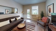 This single-floor residence offers a thoughtfully designed layout that balances comfort and functionality across multiple living areas. The living room serves as a welcoming focal point, featuring durable wood-look flooring, neutral wall tones, and a glazed exterior door flanked by a large window that fills the space with natural light and provides views of greenery outside. A wall-mounted HVAC unit ensures year-round climate control.

The kitchen is outfitted with rich dark-wood cabinetry extending to the ceiling, white countertops, and a full suite of stainless steel appliances, including a range, over-the-range microwave, dishwasher, and refrigerator. The U-shaped layout provides generous counter and storage space, making it highly practical for everyday use.

Adjacent to the kitchen, the dedicated dining area accommodates a full-sized dining table and offers a quiet, defined space for meals. The bedrooms are carpeted for comfort, each featuring sliding closets and windows that allow in natural light. One bedroom provides direct access to an in-unit laundry area with a washer included.

The bathroom is finished with wood-toned cabinetry, a white countertop vanity, a large mirror, and a tub-shower combination. Throughout, the space maintains a cohesive, contemporary aesthetic with a neutral palette and modern fixtures.