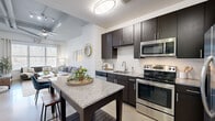 Located at 12751 Fair Lakes Cir in Fairfax, VA, this thoughtfully designed one-bedroom, one-bathroom residence offers a functional and stylish layout across a single floor. The open-concept kitchen and living area serves as the heart of the home, where dark espresso cabinetry contrasts beautifully with granite countertops and a full suite of stainless steel appliances, including a range, microwave, dishwasher, and refrigerator. A white subway tile backsplash adds a clean, modern touch, while a central kitchen island with bar seating provides additional prep and dining space. The living room receives generous natural light through large windows, highlighting the exposed beam-style ceiling details and ceiling fan overhead. The bedroom is a calm retreat, featuring a sizable window with outdoor views, plush carpeting, and soaring walls that enhance the sense of space. A dedicated closet provides practical storage. The bathroom is finished with granite countertops, dark wood cabinetry, a large mirror, and a full soaking tub with white subway tile surround. Neutral tones and clean lines are carried throughout, creating a cohesive and inviting ambiance well-suited for comfortable everyday living.