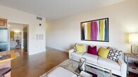 Located at 316 King St in Greensboro, NC, this one-bedroom, one-bathroom residence offers a well-designed layout that makes efficient use of its space across a single floor. The open-concept living and kitchen area is an immediate highlight, anchored by rich exposed brick walls and polished concrete floors that lend an industrial-chic character throughout. French doors open to a private balcony, flooding the living area with natural light and providing outdoor access. The kitchen features warm wood cabinetry, a central island with bar seating, track lighting, and ample counter space, flowing seamlessly into the living area for an inviting, connected feel. The bedroom is a comfortable retreat, complete with a ceiling fan, a large mirrored sliding-door closet with built-in shelving and organization, and hardwood flooring. The bathroom is well-appointed with a full soaking tub and shower combo, a warm wood vanity topped with a vessel sink, a stone-tiled mirror surround, and track lighting overhead. A hallway connects the main living spaces, completing a thoughtful and functional floor plan that balances style with everyday livability.