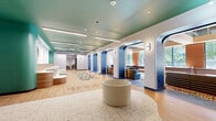Located at 1201 Rue de la Montagne in the heart of Montréal, this lounge and coworking space delivers a bold, design-forward environment tailored for productivity and comfort. The single-floor layout spans a generous footprint, offering a variety of distinct zones connected by a central hallway.

The interior is immediately distinguished by its striking color palette — teal-painted ceilings, deep navy archways with integrated LED lighting, warm terracotta tile accents, and rich wood paneling create a layered, contemporary aesthetic. Light hardwood flooring and decorative patterned rugs add warmth and texture throughout.

A bright, open lounge area features floor-to-ceiling windows overlooking tree-lined streets, with built-in bench seating, terrazzo dividers, and exposed ductwork lending an industrial-chic character. A dedicated coworking zone offers long wooden desks with elegant brass task lamps, ideal for focused work. A reception area with a curved white desk anchors the main entrance, while a glass-enclosed workspace provides a quieter setting.

Additional areas include a vibrant mailroom finished in bold orange tones with terrazzo flooring, private rooms accessed through frosted glass doors, and a teal-accented corridor leading to washroom facilities. Throughout, thoughtful lighting, curated furnishings, and cohesive design details make this a distinctive and functional professional environment.