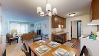 This well-laid-out two-bedroom, one-bathroom residence in Brooklyn Park, Minnesota, offers a comfortable and functional single-floor layout. The galley-style kitchen is outfitted with warm wood cabinetry, laminate countertops, a double sink, and white appliances including a dishwasher, refrigerator, and electric range, all set on easy-care hardwood-style flooring. The kitchen flows directly into a dedicated dining area, illuminated by a stylish chandelier and large enough to accommodate a full dining set — perfect for everyday meals or entertaining guests. The adjoining living room is carpeted and bright, featuring a sliding glass door that invites natural light and provides outdoor access. A hallway connects the main living areas to the two bedrooms and full bathroom. The primary bedroom offers generous proportions with plush carpeting and ample room for furnishings. The second bedroom is also carpeted and well-sized. The full bathroom features a clean, tiled shower-tub combination. Throughout the home, four closets provide excellent storage capacity. Textured ceilings and warm wood-toned trim details carry consistently through the space, lending it a cohesive and inviting character.