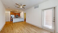 This studio in Leander, TX offers a thoughtfully designed single-floor open-concept layout that efficiently combines the living and kitchen areas into one cohesive space. Light wood-style flooring runs throughout, creating a bright, clean aesthetic complemented by crisp white walls and recessed lighting. A ceiling fan in the main living area adds both comfort and style.

The kitchen is a standout feature, equipped with warm-toned wood cabinetry, stainless steel appliances including a refrigerator with ice dispenser, a range, and a microwave. A granite-topped peninsula with an undermount sink serves as a natural divider between the kitchen and living area, offering additional prep and seating space. A tiled backsplash adds a polished finishing touch.

The studio includes two bathrooms, one of which features a full tub-shower combination with white tile surround, a wood-toned vanity with granite countertop, and wood-look tile flooring. A dedicated closet provides practical storage. Natural light enters through a windowed entry door and additional windows, keeping the space feeling open and airy. In-unit stacked laundry is also present, adding everyday convenience to this efficiently designed studio.