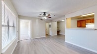 This single-floor, three-bedroom, two-bathroom home in Springdale, Arkansas offers a practical and comfortable layout with clean, neutral finishes throughout. The combined kitchen and living area serves as the heart of the home, with light wood-style flooring, a ceiling fan with light kit, and a textured ceiling. The living room opens toward a built-in shelving nook, while the kitchen is accessible via a pass-through counter. The galley-style kitchen is well-appointed with warm wood cabinetry, white countertops, a stainless steel refrigerator, an electric range, and a double sink — with a dedicated laundry area just off the back housing a full-size Whirlpool washer and dryer. The three bedrooms feature plush carpeting and windows with blinds that invite natural light. The primary bedroom includes a ceiling fan and a generous footprint. Both bathrooms are outfitted with wood-toned vanity cabinets, light countertops, a tub-shower combo, and light vinyl flooring. Additional storage is provided by two closets and overhead bathroom cabinetry. A hallway connects the private quarters to the main living space, creating a functional flow throughout this well-maintained home.