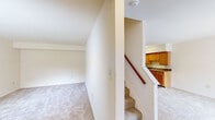 This two-story home offers a practical and well-organized layout spread across two floors. The main level features an entrance, a kitchen equipped with warm honey-toned wood cabinetry, dark granite-style countertops, a white electric range, and a full-size refrigerator set atop light wood-look flooring. Adjacent to the kitchen is a dedicated dining area, providing a clear separation between cooking and dining spaces. A staircase with a classic wood handrail connects the two levels, and a utility room and hallway round out the lower floor.

The upper level hosts all three bedrooms, each finished with neutral wall-to-wall carpeting and crisp white walls. The generously sized primary bedroom offers ample square footage and its own closet. The two additional bedrooms each feature windows that invite natural light and views of surrounding greenery. Three closets in total are distributed throughout the home, providing solid storage options. The single full bathroom features a white tiled tub-shower surround with clean, simple finishes. Throughout the home, the neutral color palette, carpeted living areas, and straightforward design create a bright, move-in ready environment that is easy to personalize.