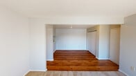 This single-floor residence offers a well-organized layout with a seamless blend of hardwood flooring and plush carpet throughout. The entry transitions into an open living and dining area, where rich hardwood floors extend underfoot and a sliding glass door floods the space with natural light while providing direct access to a private balcony with outdoor views. The adjoining kitchen is efficiently designed with ample upper and lower cabinetry, laminate countertops, a double-basin stainless steel sink, and a white range, making it a fully functional cooking space. A pass-through counter connects the kitchen to the main living area, enhancing the open feel. The bedrooms are finished with soft wall-to-wall carpet and feature generous closet storage, including sliding panel closets with built-in hanging rods. Windows fitted with horizontal blinds allow for natural light and privacy control. The bathroom includes a full tub and shower combination with classic square tile surround and a chrome curtain rod. Throughout the space, neutral wall tones, white trim, and textured ceilings create a clean, understated aesthetic that is move-in ready and easy to personalize.