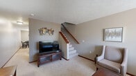 This two-story home in Sioux Falls, South Dakota offers a practical and comfortable layout spread across two floors. The main level houses the kitchen and living area, while the upper level contains both bedrooms and a hallway connecting the spaces. The kitchen is well-appointed with warm oak cabinetry, stainless steel appliances including a refrigerator, dishwasher, electric range, and over-the-range microwave, complemented by granite-toned countertops and light tile flooring. A dining area sits adjacent to the kitchen, providing a convenient space for everyday meals. The living room features plush carpeting, a textured ceiling, and a window that allows natural light to fill the room, creating a relaxed and welcoming atmosphere. Both bedrooms are carpeted and include windows that bring in natural light. The primary bedroom offers a comfortable amount of space, while the second bedroom connects to the hallway and staircase. The two bathrooms are functionally designed; one features a vanity with oak cabinetry and a walk-in shower, while the other includes a full tub-shower combination. Neutral tones and warm wood trim details are carried throughout the home, contributing to a cohesive and understated aesthetic.