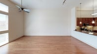 This single-floor residence offers a thoughtfully designed layout that balances open living spaces with functional private areas. The main living area features warm hardwood flooring, high ceilings, and an exposed industrial-style HVAC duct, lending a modern loft-like character. A ceiling fan adds both style and comfort to the generous open space, which flows seamlessly toward additional rooms.

The kitchen is a standout feature, showcasing rich medium-toned wood cabinetry, granite countertops, and a tile backsplash. Stainless steel appliances — including a gas range, microwave, and refrigerator — are complemented by pendant and under-cabinet lighting, creating a bright and fully equipped cooking environment. A kitchen island with additional counter space adds practicality.

The bedroom is carpeted for comfort and features elevated ceilings with a ceiling fan. It provides direct access to a dedicated bathroom, which includes a vanity with a single sink, ample mirror space, and a combined tub and shower with tile surround. A secondary carpeted room with large windows allows generous natural light to fill the space.

Completing the unit is a dedicated in-unit laundry area with a full-size washer and dryer and wire shelving above for added storage. Throughout the residence, clean white walls and consistent finishes create a bright, cohesive ambiance.