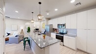 This thoughtfully designed 2-bedroom, 2-bathroom residence offers a functional and modern single-floor layout. The open-concept kitchen serves as a central highlight, featuring a large granite-topped island with bar seating, sleek white cabinetry extending to the ceiling, stainless steel appliances, and stylish pendant lighting. Light wood-look flooring flows seamlessly throughout the space, enhancing the bright, cohesive aesthetic.

The living room is comfortably sized with recessed lighting, a ceiling fan, and a glass door that invites natural light and outdoor access. Neutral-toned walls create a calm, welcoming ambiance throughout.

The primary bedroom is generously proportioned, offering multiple windows, a ceiling fan, and ample room for a full furniture arrangement. The second bedroom is equally well-appointed with closet access and an open view to the hallway. Both bathrooms are finished with granite countertops, glass-enclosed walk-in showers with large-format tile surrounds, and modern vanities — one featuring an illuminated mirror for added functionality.

The entrance and hallway provide a smooth transition between rooms, contributing to the home's efficient and intuitive floor plan. Overall, the space combines contemporary finishes with practical design for comfortable everyday living.