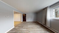 Located at 754 State St in Eaton Rapids, Michigan, this first-floor unit offers a well-organized, single-level layout with consistent finishes throughout. The kitchen is a standout feature, showcasing rich dark espresso cabinetry, dark granite countertops, a tile backsplash with a geometric mosaic pattern, a double-basin sink, and black appliances including a refrigerator and dishwasher. The space is finished with neutral ceramic tile flooring, giving it a clean and practical feel. The living area is open and bright, finished with wood-look tile flooring in a warm, natural tone and neutral gray walls that create a calm, cohesive atmosphere. A dark wood entry door and baseboard heating units are present throughout the unit. The bedroom features the same wood-look tile flooring, soft gray walls, a window with curtain panels that allows natural light in, and a wall-mounted air conditioning unit. The bathroom is thoughtfully appointed with a vessel sink set atop a rich granite vanity top, a mosaic tile backsplash, classic white hexagonal floor tile, and a tub/shower combination. The overall design is understated and functional, with consistent material choices that give the unit a unified, move-in-ready character.
