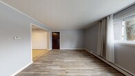 Located at 754 State St in Eaton Rapids, Michigan, this first-floor unit offers a well-organized, single-level layout with consistent finishes throughout. The kitchen is a standout feature, showcasing rich dark espresso cabinetry, dark granite countertops, a tile backsplash with a geometric mosaic pattern, a double-basin sink, and black appliances including a refrigerator and dishwasher. The space is finished with neutral ceramic tile flooring, giving it a clean and practical feel. The living area is open and bright, finished with wood-look tile flooring in a warm, natural tone and neutral gray walls that create a calm, cohesive atmosphere. A dark wood entry door and baseboard heating units are present throughout the unit. The bedroom features the same wood-look tile flooring, soft gray walls, a window with curtain panels that allows natural light in, and a wall-mounted air conditioning unit. The bathroom is thoughtfully appointed with a vessel sink set atop a rich granite vanity top, a mosaic tile backsplash, classic white hexagonal floor tile, and a tub/shower combination. The overall design is understated and functional, with consistent material choices that give the unit a unified, move-in-ready character.