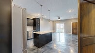 Located at 2101 Railway Ln. in Marysville, OH, this one-bedroom, one-bathroom unit delivers a modern aesthetic throughout its well-designed single floor. The most striking architectural feature is the continuous metallic epoxy flooring, which flows seamlessly through every room with a swirling, reflective finish in shades of blue, silver, and charcoal — creating a dramatic and cohesive visual identity across the entire space.

The open-concept kitchen and living area serves as the heart of the unit. The kitchen is outfitted with dark espresso cabinetry, a white subway tile backsplash, granite countertops, stainless steel appliances, and a central island with pendant lighting above — offering both functionality and style. The living area benefits from sliding glass doors that open to a private balcony, allowing natural light to fill the space and providing outdoor views of the surrounding community.

The bedroom is a well-proportioned retreat with a ceiling fan, a large window with exterior views, and clean neutral walls. A dedicated closet provides organized storage. The bathroom features a walk-in shower, a dark vanity with a white countertop, a large mirror with overhead lighting, and a tall storage cabinet, completing the unit's consistent modern design language.