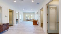 Located at 14355 N Main St in Jacksonville, FL, this thoughtfully designed single-floor office space offers a clean, contemporary aesthetic throughout. The open common area greets visitors with light wood-look flooring, recessed lighting, and a row of windows that invite abundant natural light and outdoor views. Comfortable seating arrangements with woven accent chairs create a welcoming lounge atmosphere within this central corridor.

The space includes three private offices, each carpeted and finished with neutral tones, recessed lighting, and light wood desks paired with modern ergonomic seating — ideal for focused, individual work. Two dedicated conference rooms provide distinct meeting environments: one features a striking natural wood conference table beneath a sleek linear pendant light with views to the outdoors, while the other showcases a bold marble-topped table with warm leather chairs, lending an elevated, professional ambiance.

A standout artistic element is a detailed nature-inspired mural — depicting delicate tree branches in bloom — adorning the walls of the conference room corridor, adding a touch of creativity and warmth to the overall space. A small utility area with a printer station and a herringbone-patterned wood credenza complete the functional offerings. The space balances practicality with refined design, making it a well-rounded professional environment.