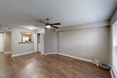 Located at 2408 Houma Blvd in Metairie, Louisiana, this single-story, one-bedroom, one-bathroom unit offers a practical and well-maintained layout across a comfortable footprint. The living room serves as the central gathering space, featuring durable wood-look flooring, neutral gray walls, white baseboards, a textured ceiling, and a ceiling fan with integrated lighting. A window with blinds allows natural light to fill the room, creating a bright and open feel. The layout flows seamlessly into the kitchen, which is outfitted with warm honey-toned wood cabinetry, granite-style countertops, a mosaic tile backsplash, white appliances including a range and refrigerator, and a stainless steel sink. A hallway connects the main living areas to the private bedroom, which is carpeted for comfort and features its own ceiling fan, a window with blinds, and ample wall space. The bathroom includes a wood-toned vanity with a granite-style countertop, wood-look flooring, and a shower-tub combination. A dedicated closet and multiple hallways provide functional storage and circulation throughout the unit. The overall design is clean and cohesive, with consistent neutral tones and practical finishes throughout.