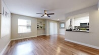 This 1-bedroom, 1-bathroom single-floor residence offers a thoughtfully designed layout that maximizes comfort and functionality. The combined kitchen and living room serves as the heart of the home, featuring warm wood-look flooring that flows seamlessly throughout the entire space. The living area is highlighted by a ceiling fan with light fixture, built-in shelving, a sliding glass door with vertical blinds, and abundant natural light streaming through multiple windows fitted with blinds. A decorative mirror accent adds visual depth to the room.

The galley-style kitchen is efficiently arranged with white cabinetry, dark countertops, stainless steel appliances including a refrigerator and dishwasher, and a pass-through window that connects to the living area.

The spacious bedroom offers a ceiling fan, a large window with exterior views, and access to a generously sized walk-in closet complete with built-in hanging rods. The bathroom features a full soaking tub and shower combination, toilet, and overhead cabinetry. Two hallways connect the rooms, contributing to the home's efficient and cohesive single-floor flow. Neutral tones and clean finishes throughout create a bright, move-in-ready ambiance.
