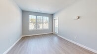 Located at 3 Orchard Lane in Swanzey, NH, this thoughtfully designed 2-bedroom, 1-bathroom unit offers a clean, contemporary aesthetic across a single floor. The open-concept kitchen and living area serves as the heart of the home, featuring crisp white cabinetry, a quartz-topped island with pendant lighting, stainless steel appliances including a refrigerator, gas range, microwave, and dishwasher, and a white subway tile backsplash. Light wood-tone luxury vinyl plank flooring flows consistently throughout the unit, complementing the soft gray walls and bright white trim.

The spacious primary bedroom offers generous square footage with large windows that invite abundant natural light and outdoor views. The second bedroom is equally well-lit, with its own window overlooking the surrounding landscape. A wide hallway connects the bedrooms to the full bathroom, which features marble-style tile flooring and a shower/tub combination. A dedicated closet provides practical storage.

The unit presents a fresh, move-in-ready condition with modern finishes, clean lines, and a neutral palette that suits a variety of interior styles. Gold-toned hardware accents on interior doors add a subtle contemporary touch throughout.
