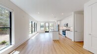 Located at 4115 Lake St in Alpharetta, GA, this thoughtfully designed one-bedroom, one-bathroom residence offers a clean, modern aesthetic across a single floor. Light hardwood flooring flows seamlessly throughout every room, complementing the crisp white walls and creating a bright, cohesive atmosphere.

The open-concept kitchen and living area serves as the heart of the home. The kitchen is outfitted with white shaker cabinetry, a classic subway tile backsplash, stainless steel appliances including a gas range, microwave, and French door refrigerator, and a large center island with a gray quartz countertop and undermount sink — ideal for both cooking and entertaining. A bank of black-framed windows floods the living area with natural light and offers views of lush, wooded surroundings.

The bedroom is a serene retreat featuring a ceiling fan, a wide picture window overlooking the tree-lined landscape, and direct access to a spacious walk-in closet with built-in wire shelving for ample storage.

The bathroom maintains the home's modern sensibility with a white vanity, gray quartz countertop, undermount sink, and a well-lit mirror framed in black — echoing the design language found throughout. A dedicated walk-in closet adds exceptional functionality to the private quarters. Recessed lighting throughout and clean architectural lines complete this polished, contemporary residence.