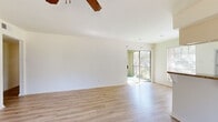 This single-story home offers a practical and well-organized layout across four bedrooms and two bathrooms. Light wood-style flooring runs throughout the home, creating a cohesive and clean aesthetic in every room. The open living area is bright and airy, with natural light streaming through large windows and a sliding glass door that leads to a private balcony overlooking lush greenery — a standout feature of the space. Ceiling fans are present in the living room and bedrooms, adding both function and a classic touch to the interior.

The kitchen is efficiently arranged with warm cabinetry, a tile backsplash, granite countertops, white appliances, and a peninsula that connects seamlessly to the living area, making it ideal for everyday use and entertaining. The bedrooms are well-proportioned, each featuring the same light flooring and generous windows that invite natural light. The primary bedroom is notably spacious and includes a ceiling fan.

Both bathrooms are finished with white cabinetry, rich granite countertops, large vanity mirrors, and contemporary lighting fixtures. The overall design is clean and neutral, offering a bright, move-in-ready environment with consistent finishes throughout.