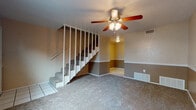 Located at 101 Redwater Rd in Wake Village, Texas, this two-story home offers a practical and functional layout across two well-defined levels. The main floor features a spacious carpeted living area anchored by a ceiling fan with integrated lighting. A carpeted staircase with white baluster railing connects the main level to the upper floor, while tile flooring marks the entryway. The walls throughout the main level display a two-tone paint treatment, with a lighter upper half and a warm tan lower half divided by a crisp white chair rail — a detail that carries consistently through multiple rooms.

Upstairs, the generously sized bedrooms continue the carpeted flooring and two-tone wall design, each equipped with a ceiling fan. Natural light filters in through blinded windows, contributing to a bright and comfortable atmosphere. One of the upper-level rooms features an adjoining doorway, suggesting a connected closet or en-suite access.

The bathroom includes a full-size soaking tub with a tiled surround in clean white, complemented by chrome fixtures. HVAC vents are present throughout, indicating a central air and heating system. The home's consistent design elements — including the repeating ceiling fans, chair rail molding, and neutral color palette — provide a cohesive and livable environment across both floors.