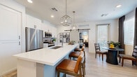 Located in Gilbert, AZ, this thoughtfully designed one-bedroom, one-bathroom residence offers a seamless blend of modern style and functional living across a single floor. The open-concept kitchen and living area serves as the heart of the home, anchored by a striking blue-accented kitchen island topped with white quartz and seating for multiple bar stools. White shaker cabinetry, stainless steel appliances, a tile backsplash, and geometric pendant lights complete the kitchen's clean, contemporary aesthetic. A sliding barn door adds a rustic-modern touch, leading between spaces with ease. The living room is bright and welcoming, featuring large windows that invite natural light and a ceiling fan overhead, creating a comfortable, airy atmosphere. A dedicated dining area and a built-in desk nook provide additional functionality. The spacious primary bedroom offers light wood-tone flooring, a ceiling fan, and glass doors that open to the outdoors, lending the room a serene, connected feel. The full bathroom features white cabinetry, a quartz vanity, and a walk-in closet. A dedicated laundry room with a full-size washer and dryer adds everyday convenience. Light wood-tone flooring runs consistently throughout, tying the entire space together with a warm, cohesive finish.