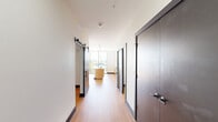 Located on the fourth floor at 330 S Shelby St in Louisville, KY, this one-bedroom, one-bathroom unit offers a thoughtfully designed single-level layout with modern finishes throughout. The entryway opens into a bright hallway with warm hardwood-style flooring that flows seamlessly through the main living areas.

The kitchen is a standout feature, showcasing light maple cabinetry, white quartz countertops, a subway tile backsplash, stainless steel appliances including a gas range and full-size refrigerator, and a central island with a sink. A floor-to-ceiling window floods the kitchen with natural light and provides open views of the surrounding Louisville streetscape.

The living room is clean and versatile, featuring recessed lighting, a distinctive black sliding barn door, and a pass-through window detail that adds architectural character. The bedroom offers a comfortable, private retreat with dedicated closet space.

The bathroom is finished with bold dark hexagonal floor tile, warm wood cabinetry, a white vanity top, and black hardware accents — including wall-mounted lighting and a towel ring — creating a stylish, contemporary feel. An in-unit laundry area adds everyday convenience. The overall design balances modern urban aesthetics with functional, efficient use of space.