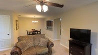 Located at 4223 I-20 Frontage Rd in Vicksburg, Mississippi, this single-floor property offers a functional and comfortable layout designed for everyday living. The open-concept living and dining area serves as the heart of the home, where soft carpeted flooring and neutral-toned walls create a warm, inviting ambiance. A decorative ceiling fan with integrated lighting anchors the living space, while an elegant chandelier illuminates the adjacent dining area, which comfortably accommodates a dining table and chairs. The living room provides ample space for seating and entertainment, with room for a media console and television. A pass-through opening connects the main living area to the kitchen, offering a sense of openness while maintaining a defined separation between spaces. The kitchen features dark cabinetry and is accessible via a dedicated entry from the main living corridor, providing both convenience and practicality. The overall layout is straightforward and efficient, making excellent use of the available footprint. The consistent color palette and understated finishes throughout give the space a cohesive, well-maintained character that is both functional and welcoming.