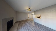 This single-floor unit at 6910 S Cockrell Hill presents a clean, modern aesthetic throughout its open layout. The living area is anchored by light gray wood-look flooring, a ceiling fan with integrated lighting, and a fireplace along one wall, creating a comfortable and functional gathering space. A pass-through peninsula connects the living area to the kitchen, enhancing the open-concept feel.

The kitchen is well-equipped with white shaker-style cabinetry, light quartz countertops, a gray tile backsplash, and stainless steel appliances including a range, microwave, dishwasher, and refrigerator. The galley-style layout maximizes counter and storage space efficiently.

A separate room accessed via French doors provides additional flexible living space, filled with natural light from the glass-paned entry. The bedroom features plush carpet flooring, a ceiling fan, a natural-light window, and direct access to a closet.

Two bathrooms serve the unit: one features a tiled tub-shower combination with warm earth-tone tile, while the second offers a walk-in tiled shower with light gray tile and wood-look flooring. Both bathrooms are finished with brushed nickel fixtures, maintaining a cohesive, contemporary style throughout the unit.