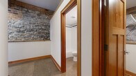 Located at 330 E Ninth St in Saint Paul, MN, this one-bedroom, one-bathroom unit offers a compelling mix of historic industrial character and thoughtful modern updates. The space is defined by its striking exposed stone masonry walls, which lend a raw, textural authenticity throughout. Polished and stained concrete flooring runs continuously across the single level, complemented by warm wood baseboards and trim that add contrast and refinement.

The main living area is open and versatile, featuring exposed ductwork, a ceiling fan, and rustic reclaimed timber columns and beams that speak to the building's storied past. A compact kitchen occupies one end of the space, equipped with stainless steel appliances including an electric range and over-the-range microwave, white cabinetry, and a stone-look backsplash that ties in with the surrounding masonry.

The bedroom offers a cozy footprint with recessed lighting and a skylight that draws in natural light from above. A dedicated closet provides practical storage. The hallway connects the rooms efficiently, with the exposed stone wall continuing as a design feature.

The bathroom is cleanly finished with white subway tile surrounding a soaking tub and shower combination, accented by a mosaic tile border and built-in niche, alongside chrome fixtures. This unit delivers an authentic urban loft aesthetic rooted in Saint Paul's architectural heritage.