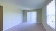Located at 4695 Braddock Ct in Columbus, Ohio, this single-floor property offers a straightforward, functional layout designed for comfortable everyday living. The interior is finished with soft, neutral-toned walls and wall-to-wall carpeting throughout, creating a clean and cohesive aesthetic. A standout feature of the main living area is the full-width sliding glass door fitted with vertical blinds, allowing natural light to filter into the space while offering easy access to the outdoors. The room is generously proportioned, providing ample space for a variety of furniture arrangements. The white baseboard trim provides a crisp contrast against the light carpeting, contributing to the room's airy, understated feel. Ceiling-mounted HVAC vents suggest a central climate control system, adding to the overall comfort and practicality of the home. The single-floor layout ensures seamless movement throughout the space, making it accessible and easy to navigate. The overall ambiance is calm and neutral, offering a versatile backdrop that can be personalized to suit a range of styles and preferences.