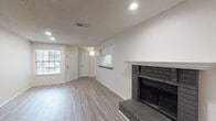 This single-story, two-bedroom, two-bathroom residence in Jacksonville, Florida (32256) offers a clean, updated interior with a cohesive neutral palette throughout. The main living area is a standout space, anchored by a classic brick fireplace with a white-painted mantel and raised hearth, providing a warm focal point. Light wood-tone luxury vinyl plank flooring runs throughout the living area, complemented by recessed lighting and a textured ceiling. A pass-through window connects the living room to the kitchen, enhancing the open feel of the space.

The galley-style kitchen is efficiently designed, featuring white cabinetry with brushed nickel hardware, dark granite-style countertops, and black appliances including a range, microwave, refrigerator, and dishwasher. A pantry or utility closet is accessible at the end of the kitchen corridor.

The bedrooms are well-proportioned, with one room showcasing darker hardwood-style flooring and natural light from a window, while another includes a ceiling fan and additional window. Both bathrooms are finished with granite-topped vanities, white cabinetry, and tub-shower combinations with tiled surrounds and light vinyl flooring.