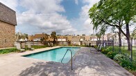 Located at 2727 S Rhode Island Ave in St. Louis Park, Minnesota, this outdoor pool area serves as a welcoming recreational amenity set within a well-maintained residential community. The centerpiece is a generously sized rectangular swimming pool with clear, blue-tinted water, featuring a depth range that accommodates both shallow and deeper swimming. The pool is finished with classic tiled edging and includes metal entry rails for convenient access.

Surrounding the pool is a spacious concrete patio deck that provides ample room for relaxation and movement. Several lounge chairs are arranged along the poolside, offering residents a comfortable space to unwind outdoors. The area is enclosed by a black iron fence, providing both security and a defined boundary for the space.

Mature trees frame the perimeter of the pool area, offering natural shade and contributing to a pleasant, park-like atmosphere. Seasonal plantings and greenery add color and vibrancy along the fenced borders. The adjacent multi-story brick and stucco residential buildings are visible in the background, reinforcing the community-oriented character of the space.

Overall, the pool area presents a clean, functional, and inviting outdoor environment well-suited for warm-weather recreation in the heart of St. Louis Park.