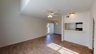 Located at 833 S University Blvd in Mobile, Alabama, this two-floor residence offers a functional and well-appointed layout with a clean, neutral aesthetic throughout. The main living area on the lower level features rich wood-style hardwood flooring, a ceiling fan with light fixture, and a sliding glass door fitted with vertical blinds that allows abundant natural light and provides access to an outdoor area. A pass-through countertop window connects the living and dining area to the kitchen, enhancing the open feel of the space. The kitchen is equipped with black appliances, including a full-size refrigerator and an electric range, complemented by white cabinetry and ample counter space. The bathroom is finished with white tile surrounding a full tub-shower combination, a single-sink vanity with white cabinetry, and wood-style flooring. The upper floor features plush carpeting, a ceiling fan, a pendant light, and its own sliding glass door offering views of the surrounding greenery. Additional rooms on the upper level are carpeted and bathed in natural light from windows with blinds. Vaulted ceilings on the upper level contribute to an open, airy atmosphere. The staircase connecting both floors is carpeted, providing a cohesive transition between levels. Overall, the space presents a bright, neutral, and move-in-ready environment.